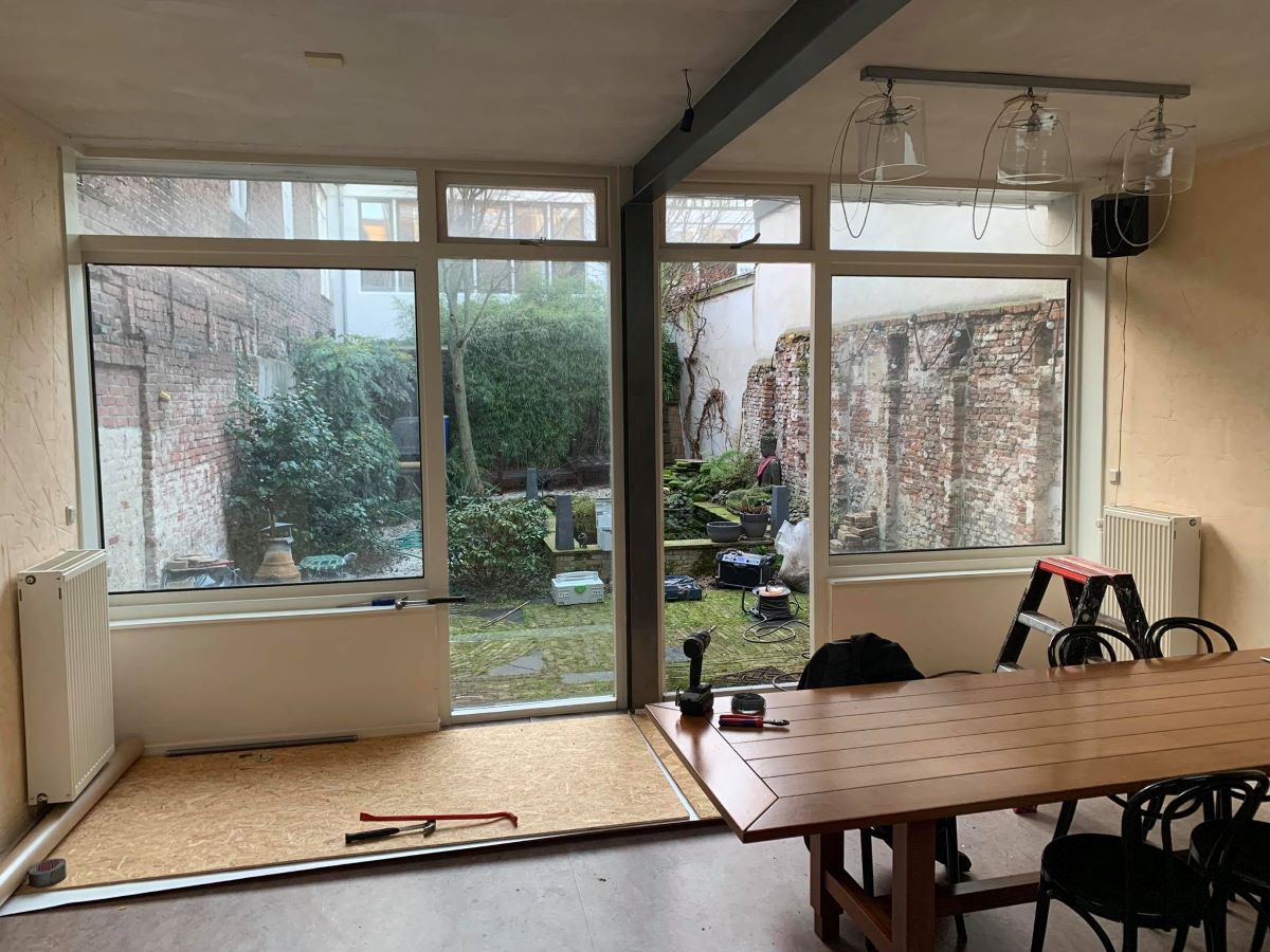 Foto van de achtergevel met een tuindeur voor de renovatie met Solarlux glazen vouwwanden