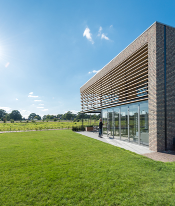 Højisoleret foldedør med store glaspartier, som giver et uforstyrret blik ud over store grønne arealer og et smukt udseende af hjemmet set udefra.