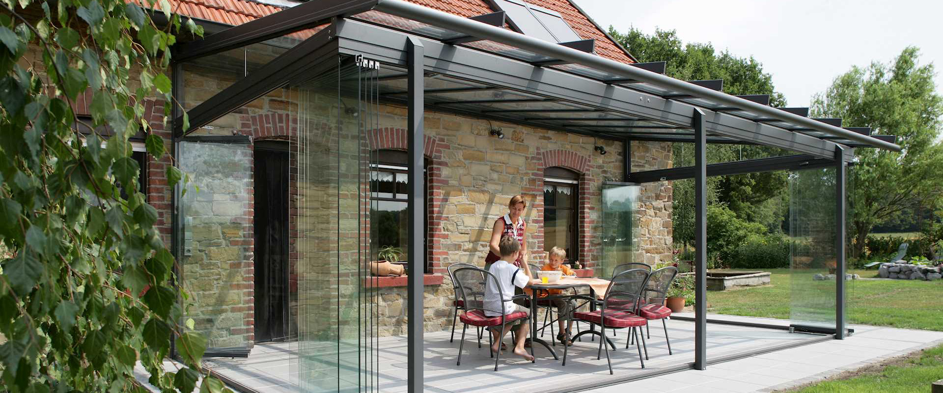 Familie sitzt unter geöffnetem Kaltwintergarten