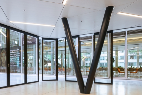 Frau öffnet die Glas-Schiebewand eines Geschäftseinganges