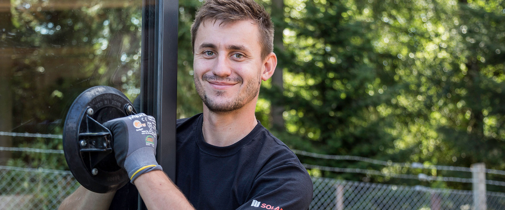 lächelnder Solarlux Mitarbeiter installiert Solarlux Glas System