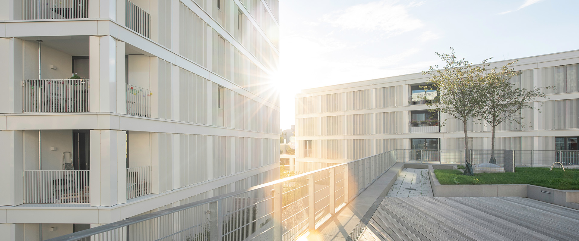 Sohne geht unter zwischen zwei modernen Gebäuden mit SL 25 XXL Balkonverglasung