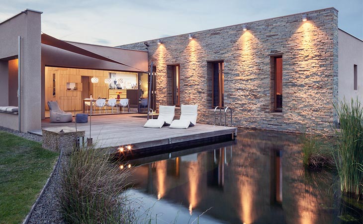 En terrasse, hvor man kan gå direkte ud gennem en foldedør med store glaspartier fra Solarlux. Foldedøren har usynlig ramme og paneler.