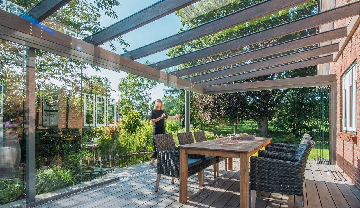 Person öffnet Solarlux Aura Glass Haus mit Blick in den Garten