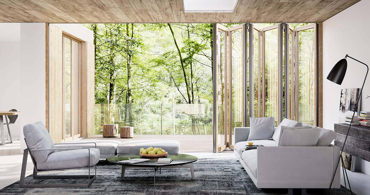 Vardagsrum med soffa och fåtölj i förgrunden och öppnat Woodline vikparti i bakgrunden med terrass och grön natur utanför. 