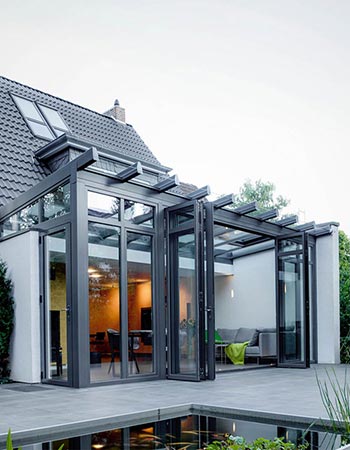 Elegant vinterhave i aluminium med glastag og foldedør, som åbner op for terrassen. Vinterhaven er skræddersyet til huset, som det er placeret i forlængelse af.