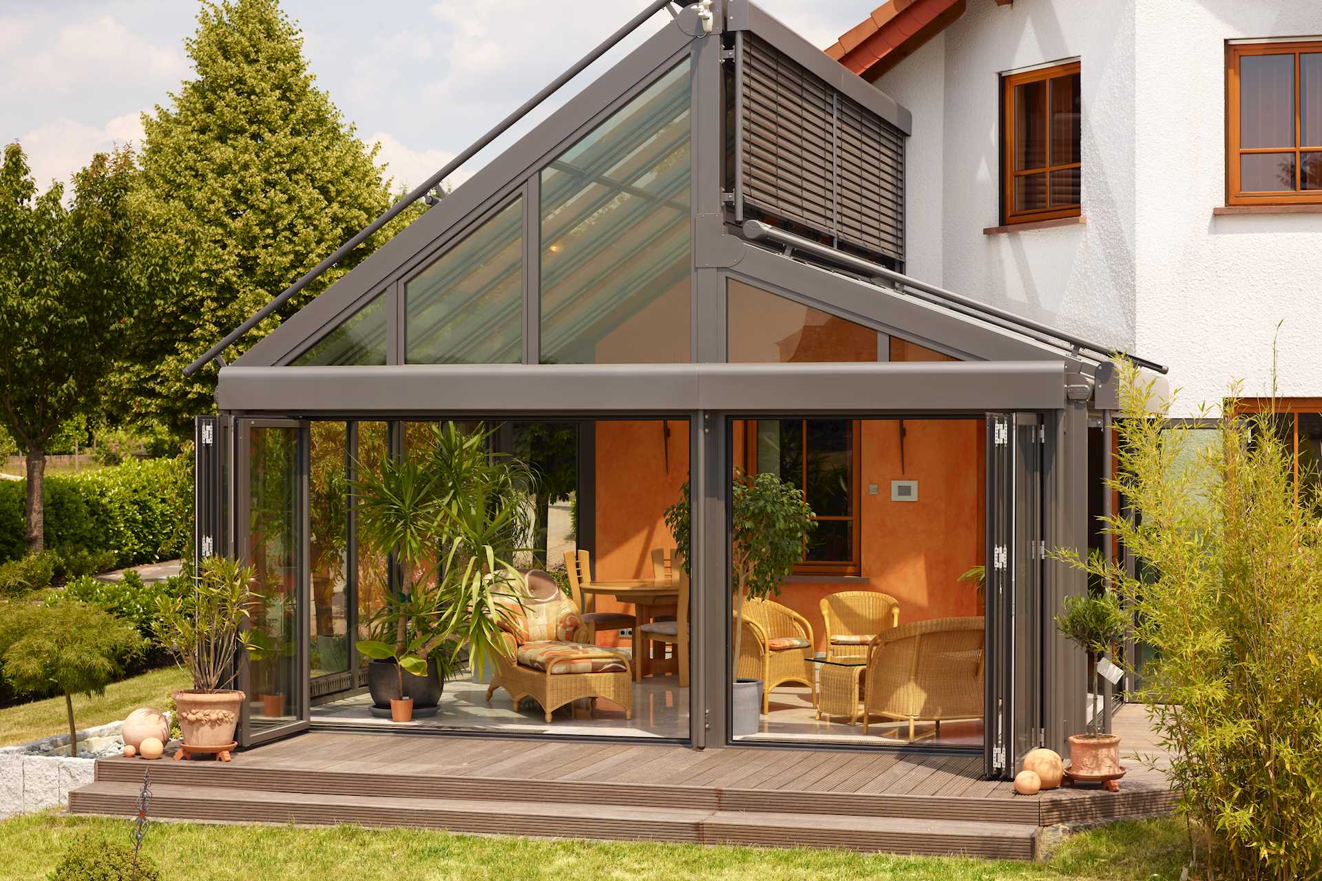 Ein Wintergarten mit asymmetrischem Dach und geöffneten Türen.