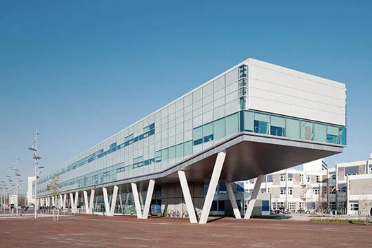 Uitzicht op een openbaar gebouw met veel ramen, dat op stalen draagconstructies staat