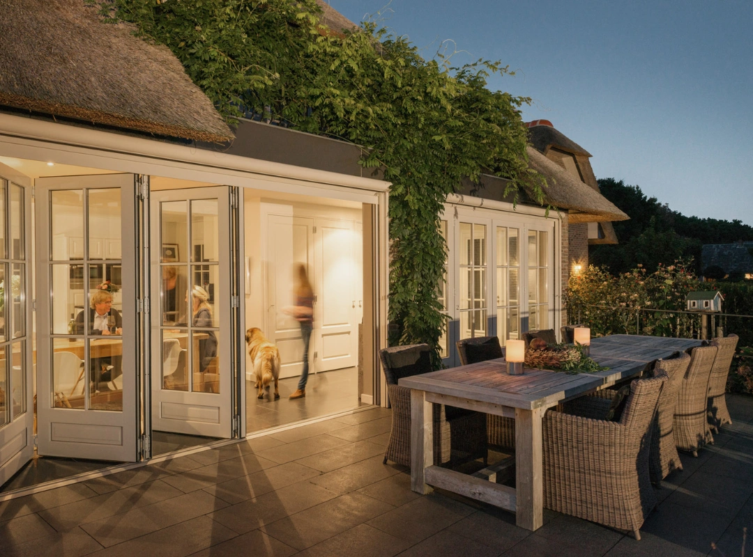 Foldedør fra Solarlux med udgang til terrasse, om aftenen i en hyggelig sommerhushave