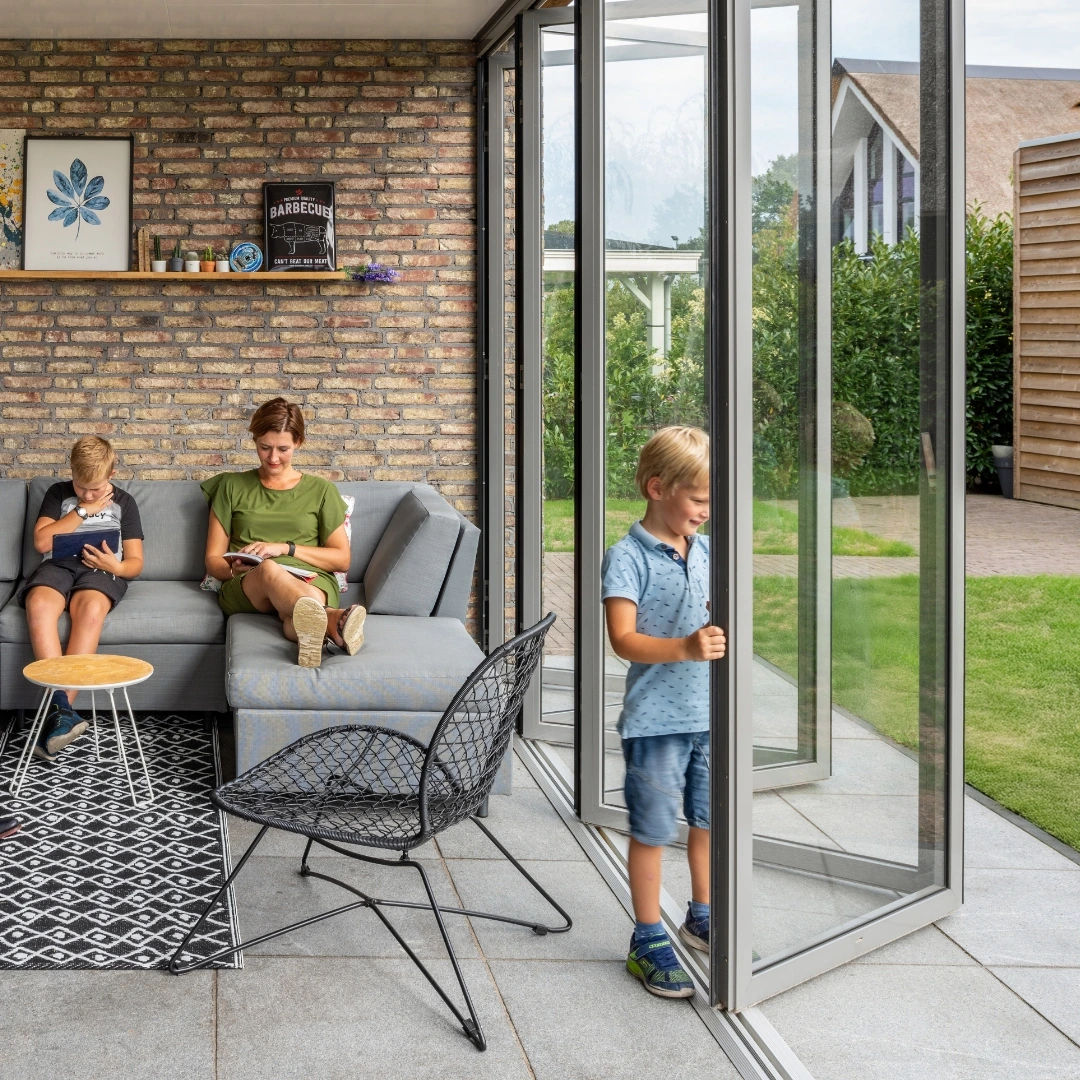 Familie sitzt neben einer half geöffneten Glasfaltwand SL 45