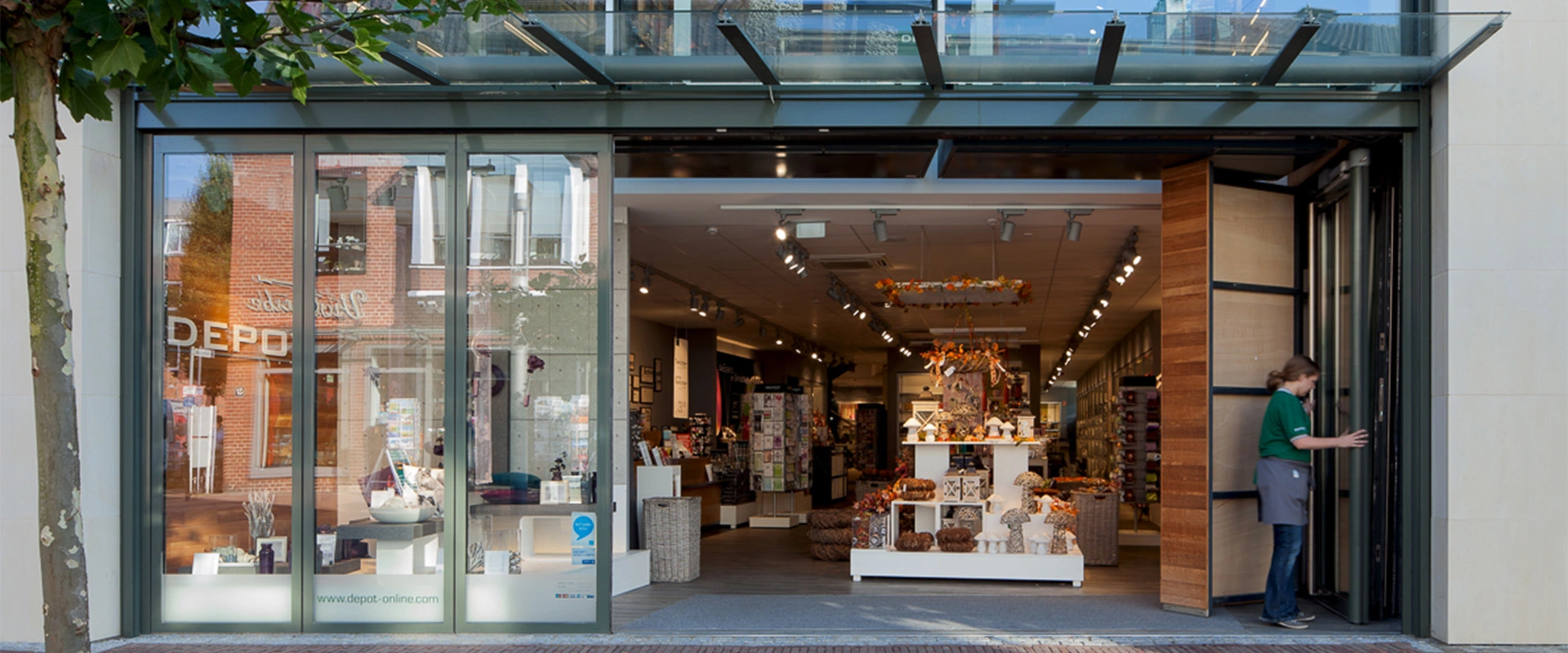 Frau öffnet Glas Faltwand verbaut im Geschäftseingang