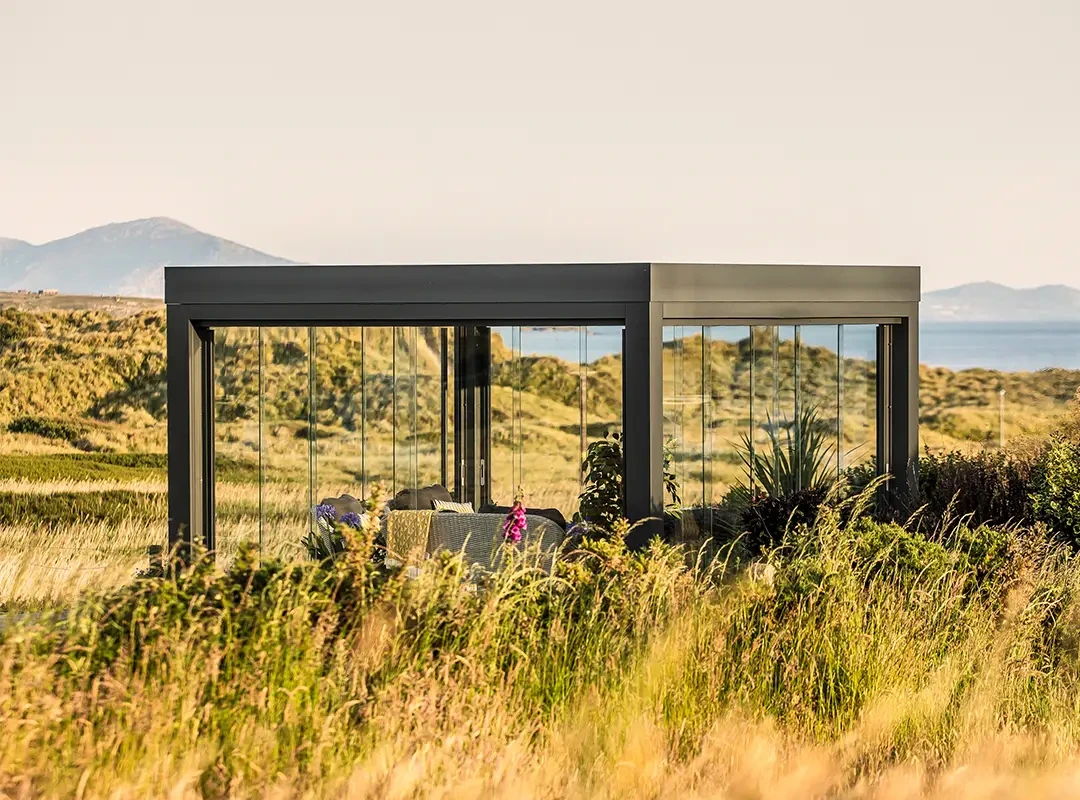 Fritstående udestue i åbent landskab.