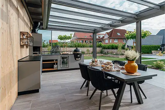 Eine Outdoorküche im Garten mit gläsernem Dach und einem gedeckten Tisch