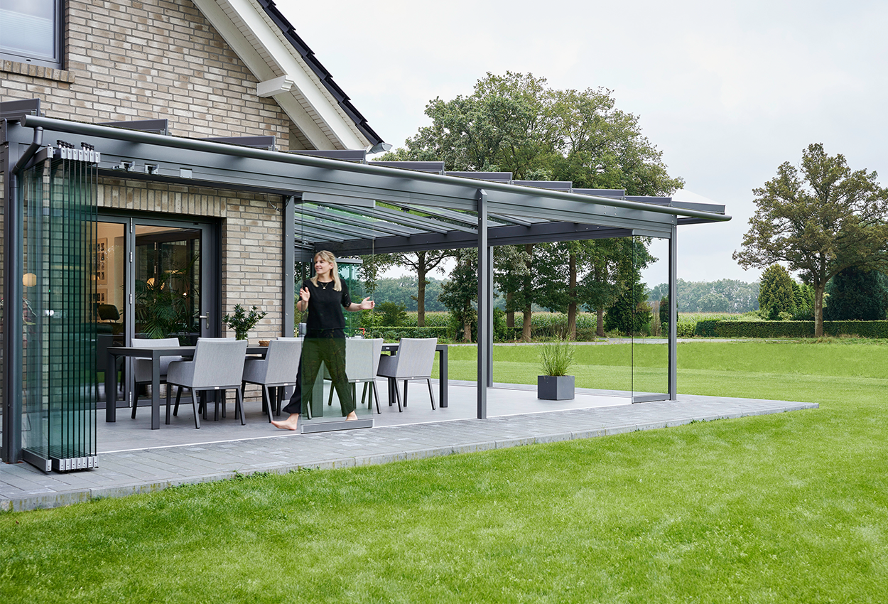 Rummelig udestue med spiseplads og glasdøre, der kan åbnes.