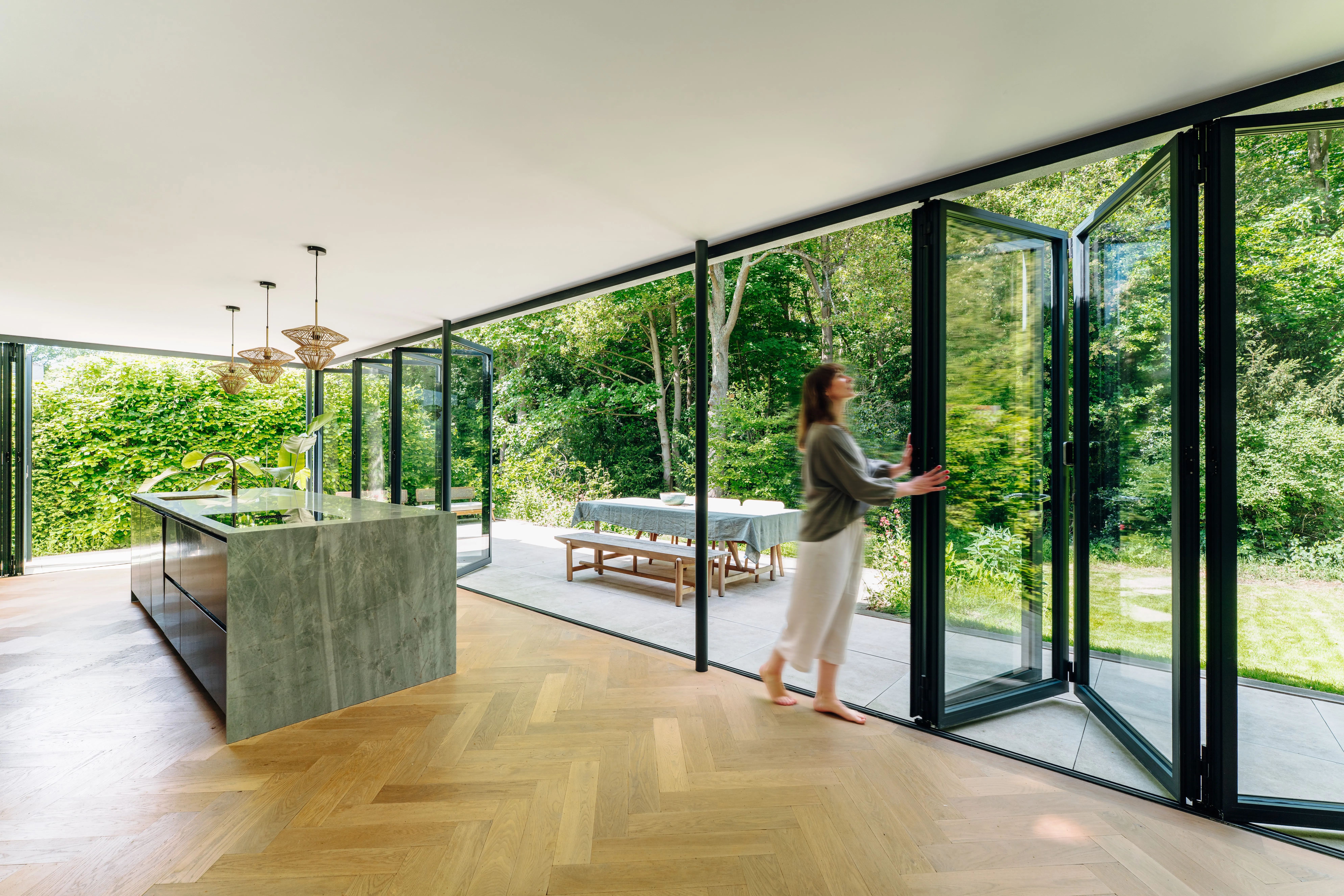 Solarlux glazen vouwwanden verbinden de woonkeuken met de tuin