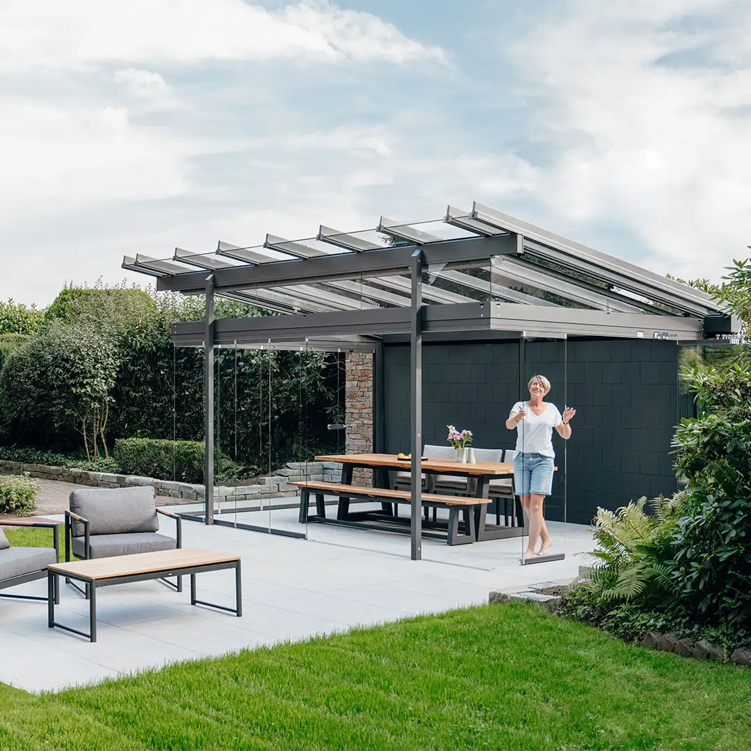 De vrouw opent schuifwanden van haar Solarlux glashuis in de tuin