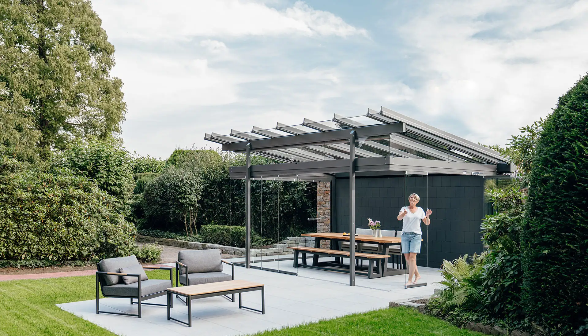 De vrouw opent schuifwanden van haar Solarlux glashuis in de tuin