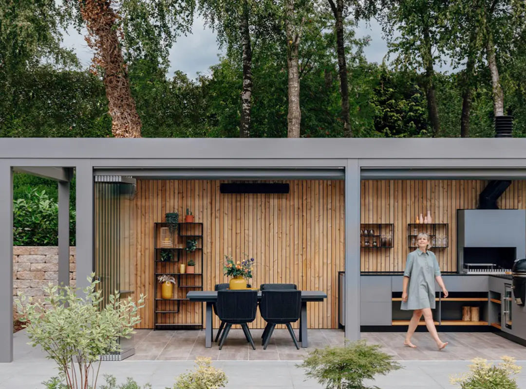 Stor uterum med platt tak som täcker utekök och matplats.