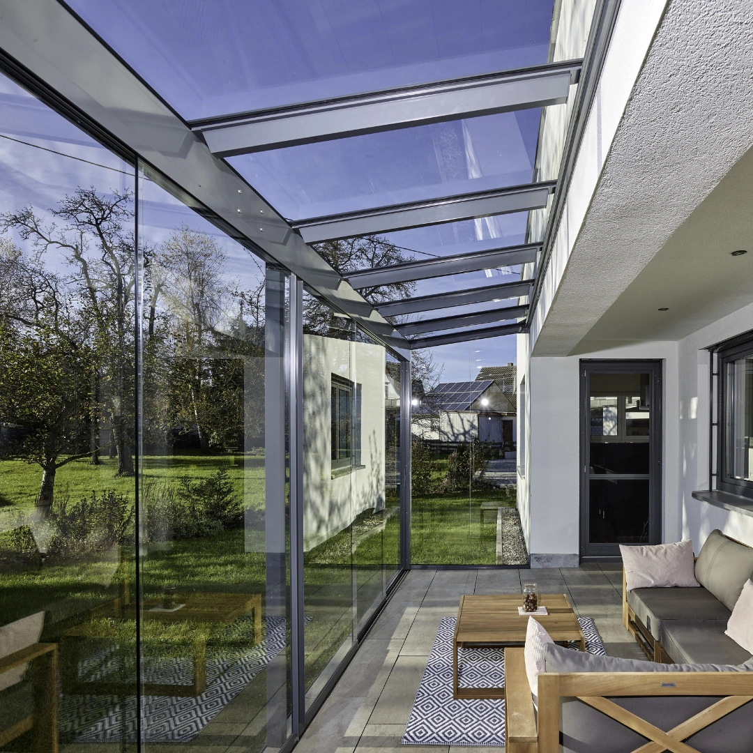 Stilren udestue i glas fra Solarlux af modellen SDL Alerio, med udsigt til haven.