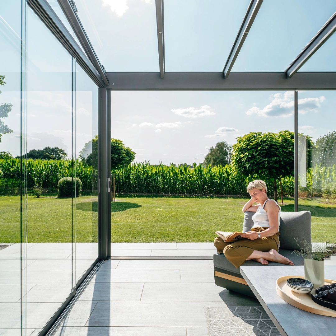 Stilren udestue i glas fra Solarlux med udsigt til haven på en smuk sommerdag