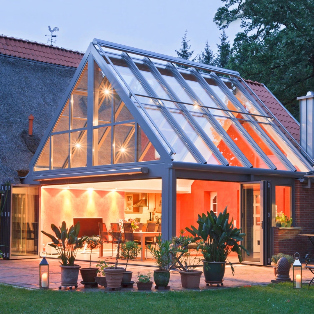 Upplyst isolerat uterum med sadeltak intill en historisk gårdsbyggnad. 