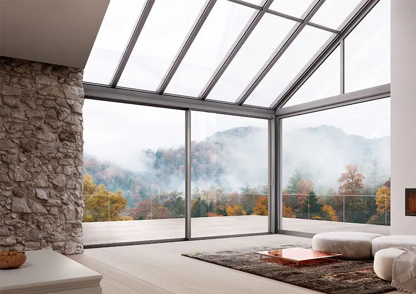 Véranda Solarlux avec baies vitrées coulissantes et vue panoramique sur une forêt verdoyante