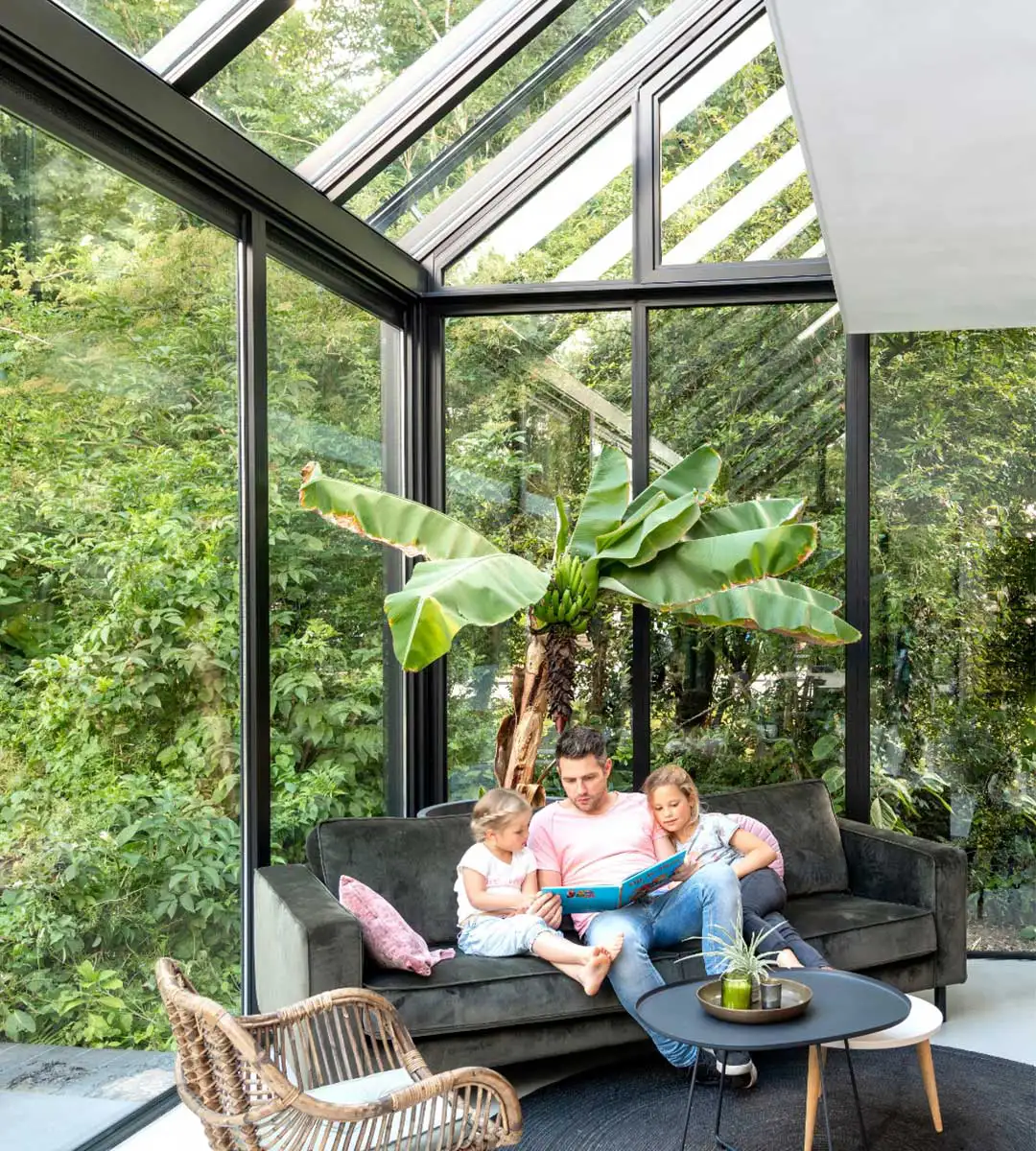 Vater ließt Kindern im Wintergarten-Wohnzimmer ein Buch vor